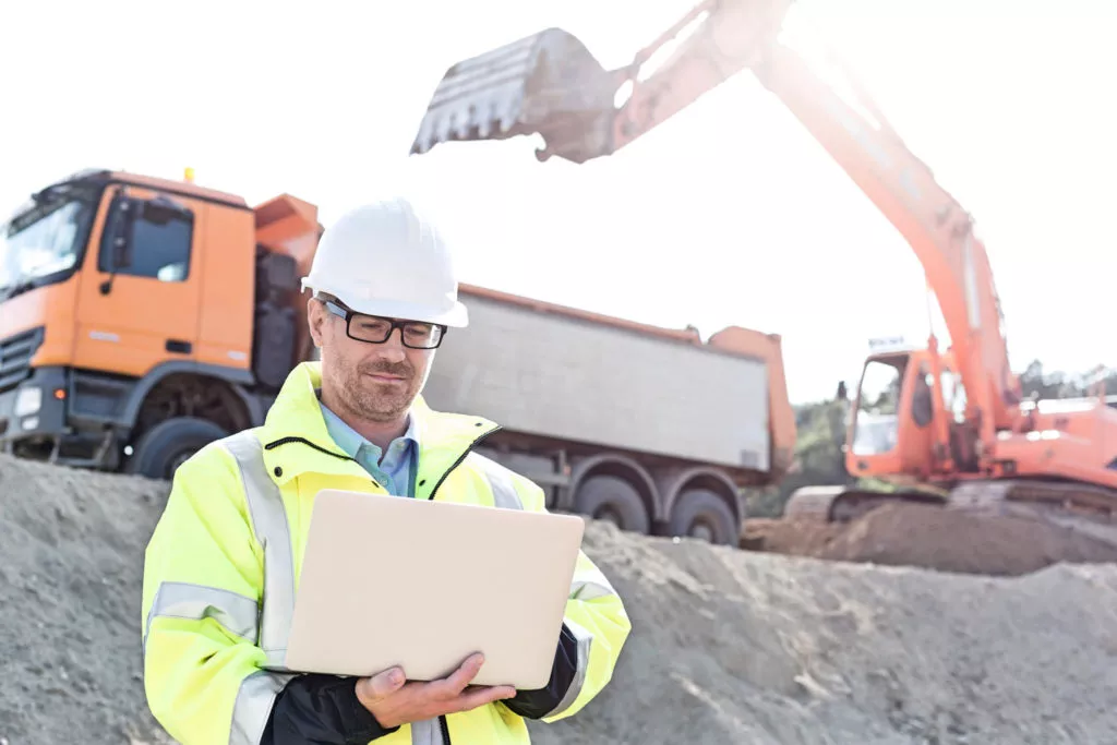 Supervisor using laptop at construction site on sunny day