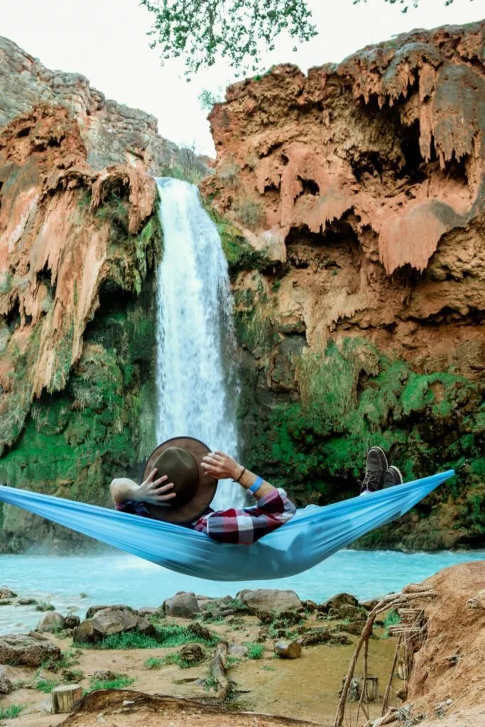 man in hammock in front of waterfall