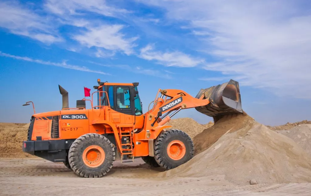 orange excavator on a brown hill 