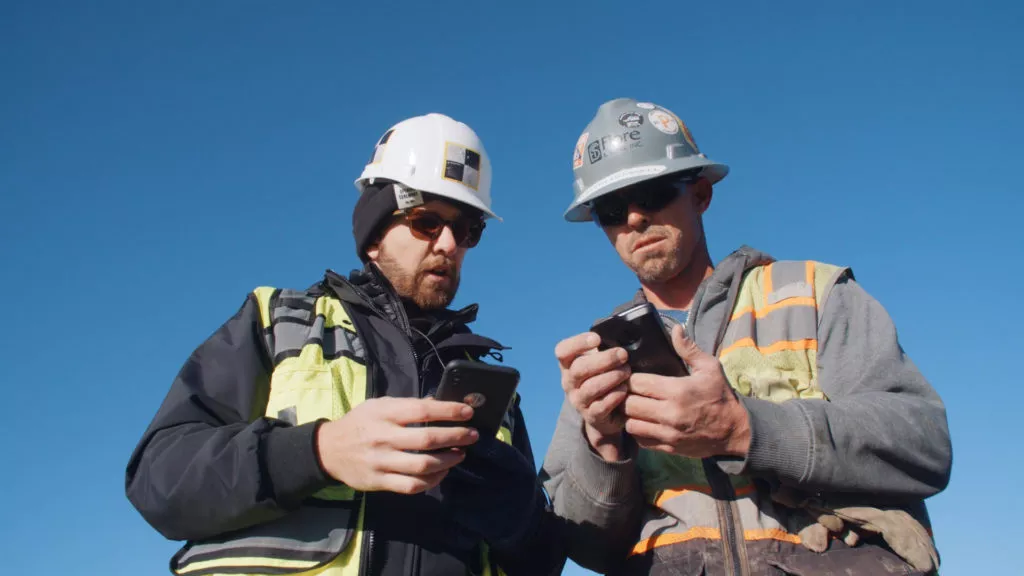 two construction workers looking at their phones